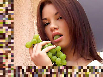 Beautiful teenager with sweet tits eats grapes outdoors