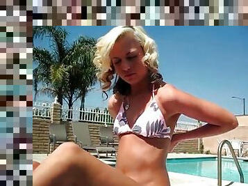 Sexy blonde bikini girl tans poolside
